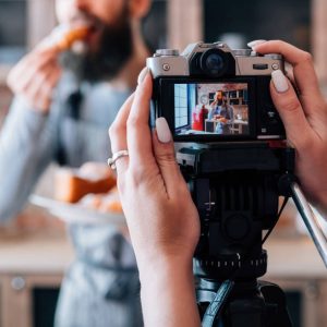 Homemade pastries. Cooking hobby. Blogging lifestyle. Pleased man eating fresh croissant. Woman with camera.